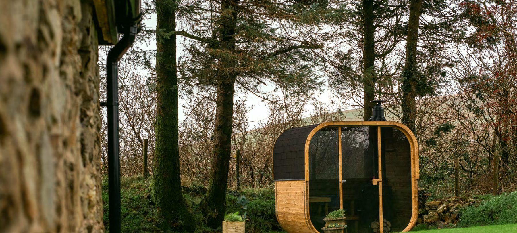 Hekla Cube Sauna neben einem Steinhaus